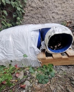 Example of a cat shelter made of plastic barrels and placed on a wooden pallet. 